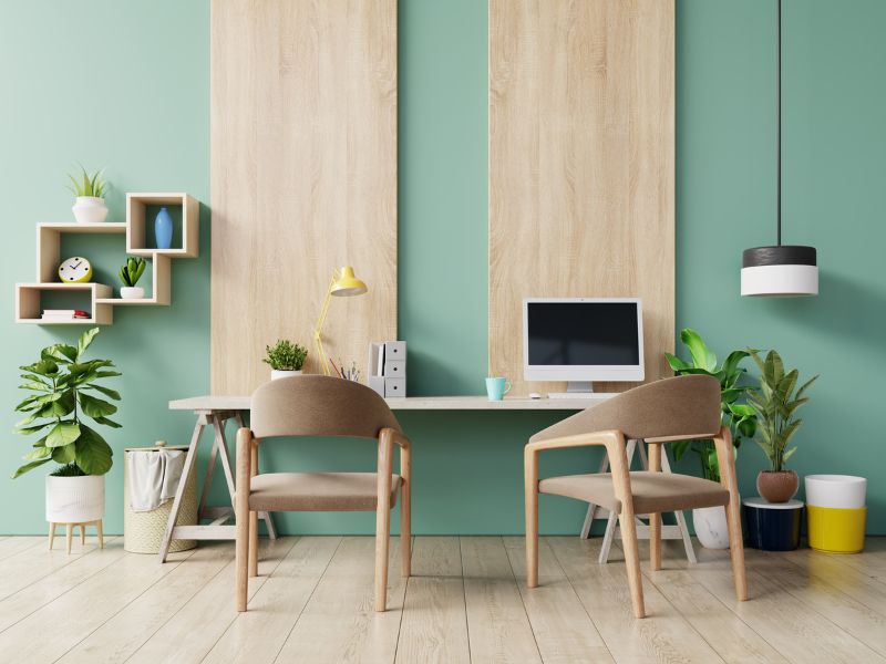 Zeleni zid sa drvenim panelima, radni sto, stolice i biljke – sklad boja za radni prostor koji stvara osećaj mira.